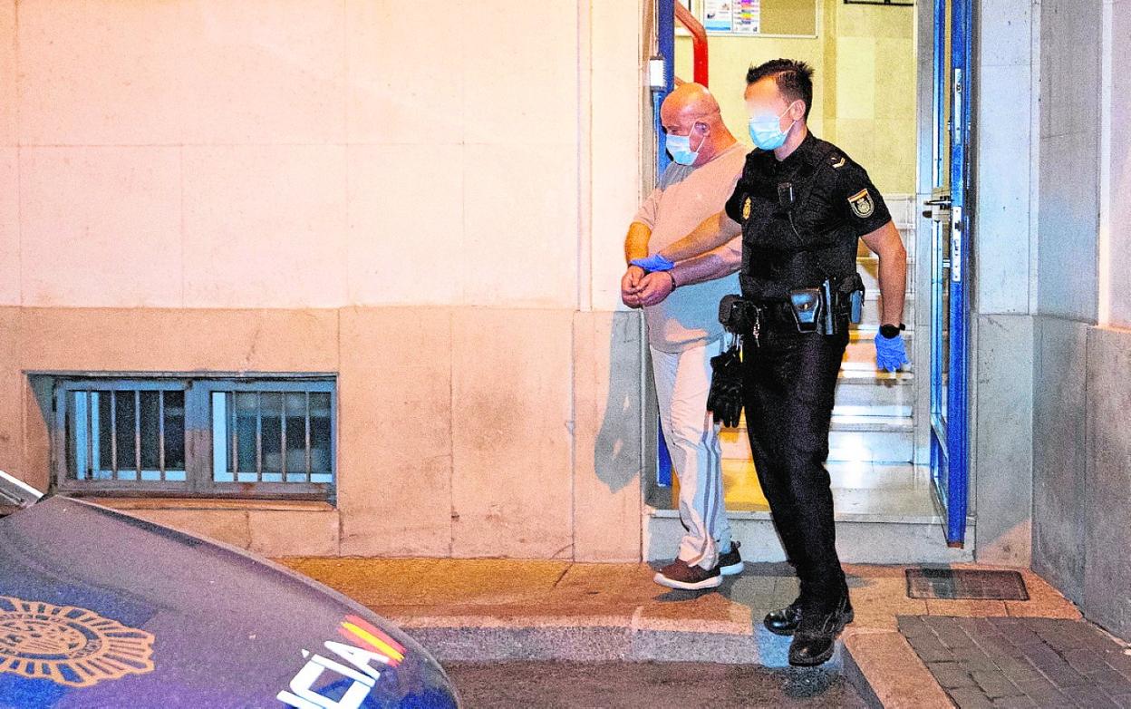 Un agente traslada al presunto autor del crimen, tras entregarse y reconocer la agresión.