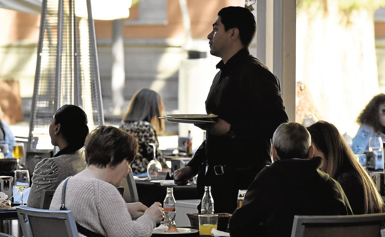 Un camarero atiende a unos clientes en una terraza en el centro de Murcia.