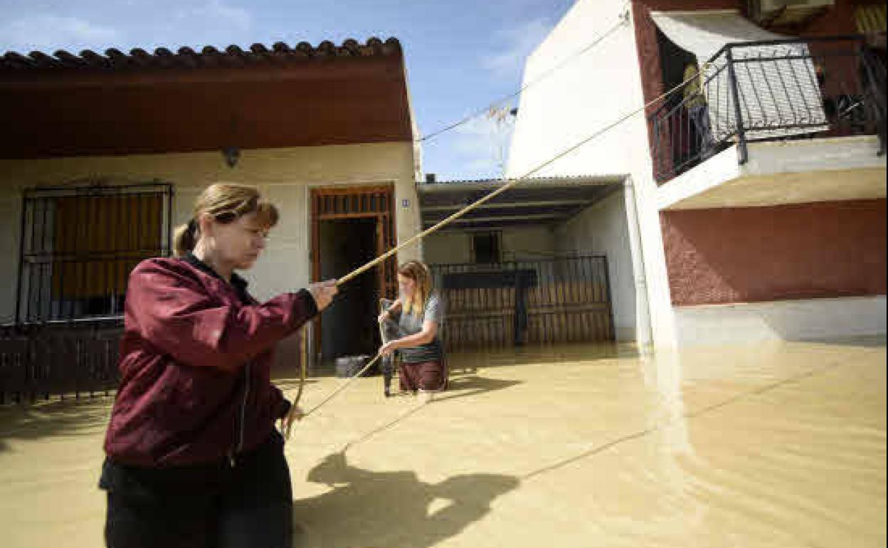Dos vecinas de Alquerías se sujetan con cuerdas a un balcón para no ser arrastradas por la corriente de agua, durante las inundaciones del año pasado.