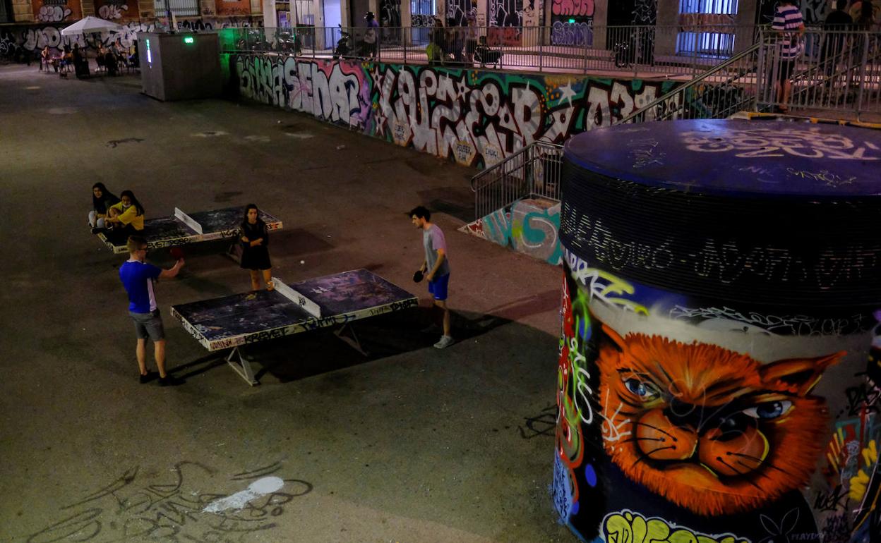 Unos jóvenes juegan sin mascarilla, pero manteniendo la distancia de seguridad, al ping-pong en un parque del barrio barcelonés del Raval.