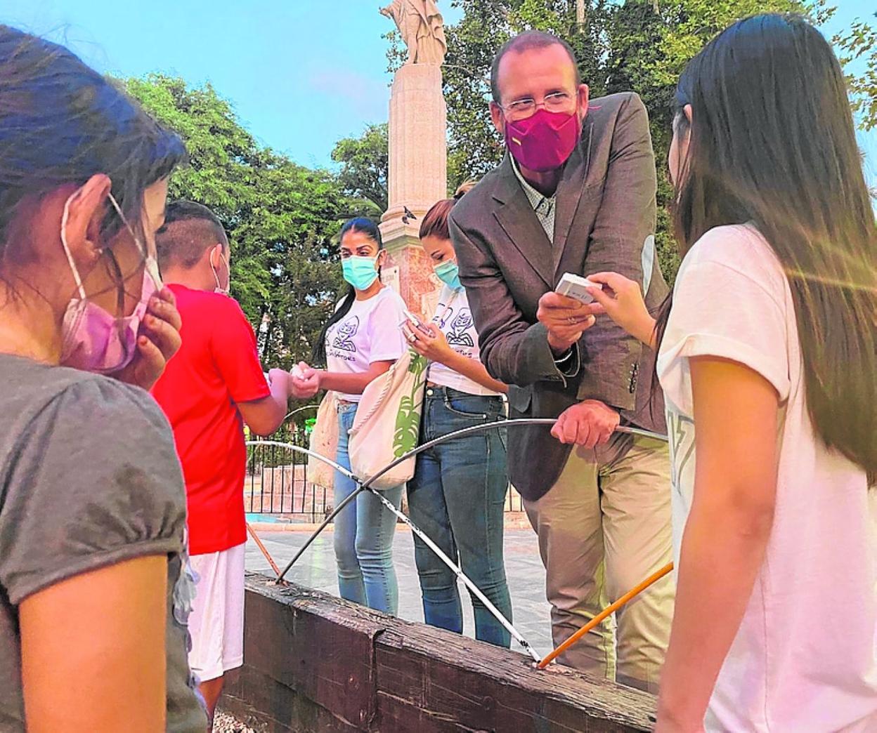 El edil Guillén entrega un portamascarillas a una niña. 