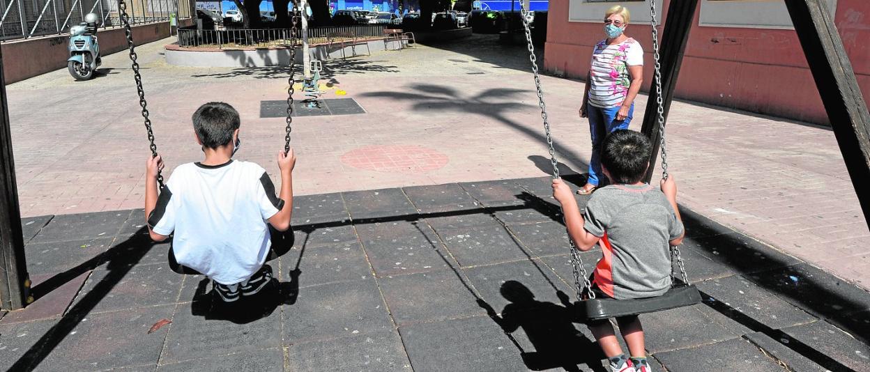 Dos niños al cuidado de su abuela, ayer, en un parque cercano al colegio Federico de Arce, en la Ronda Norte de Murcia. 