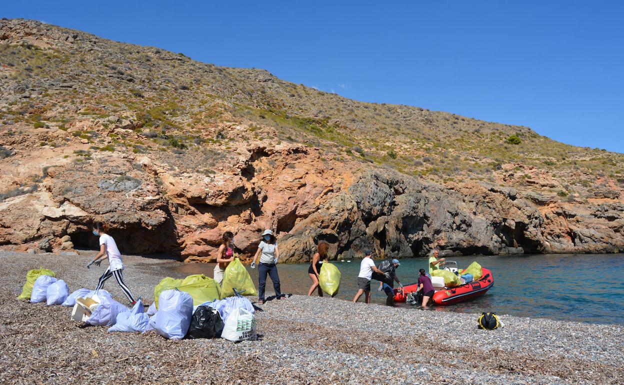 Voluntarios de ANSE y Rivemar cargan una embarcación neumática con bolsas de basura en Cala Salitrona (Cabo Tiñoso, Cartagena).