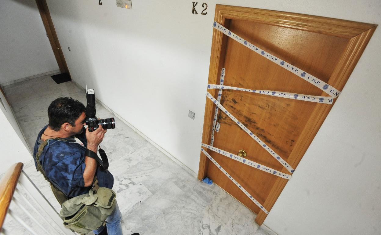 Un fotógrafo toma unas imágenes de la vivienda de la víctima con el precinto policial.