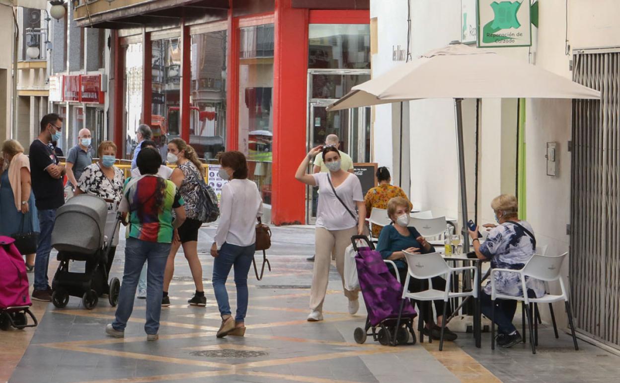 Ciudadanos caminan por la calle Corredera junto a una terraza y comercios. 