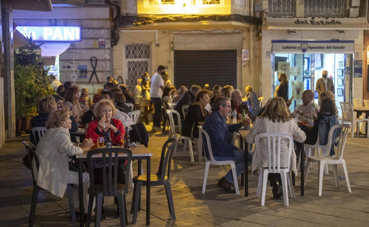 Clientes disfrutan del último día de bares abiertos, antes del parón de al menos catorce días, sentados en la terraza de Pani, en la Puerta de Murcia, al anochecer.