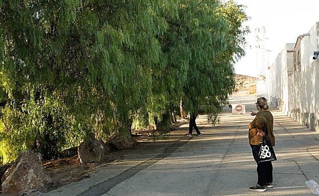 Una mujer señala el lugar en el que apareció el cadáver de la joven, junto al cementerio.