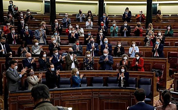 Los diputados del PSOE y Unidas Podemos aplauden a la ministra María Jesús Montero tras la votación.
