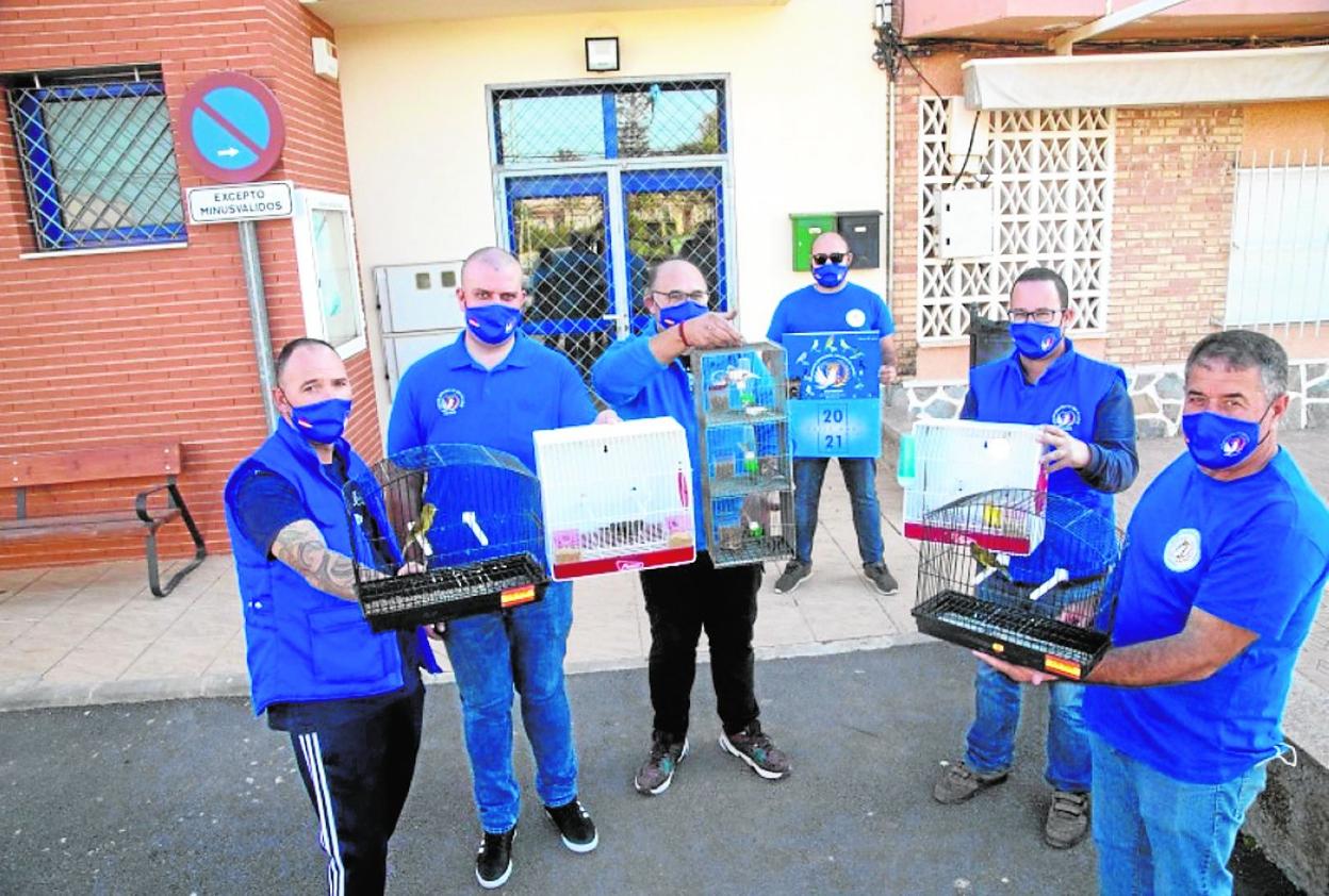 Seis directivos de la asociación ornitológica posan con sus canarios y sus jaulas a las puertas del local social de Las Lomas de El Albujón.