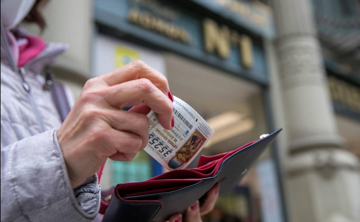 Una mujer guarda en la cartera en décimo de lotería de Navidad. 
