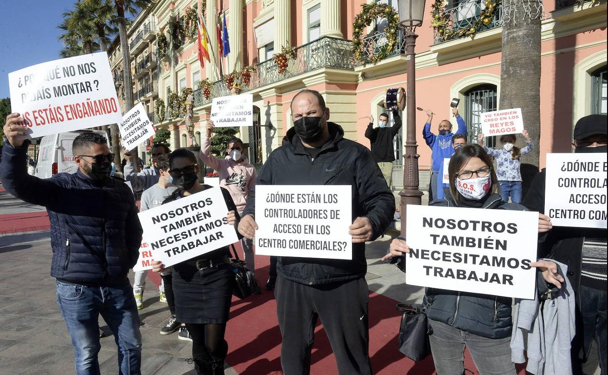 Un grupo de feriantes, este martes, en la peurta del Ayuntamiento con carteles de protesta, un tambor y alguna cacerola.