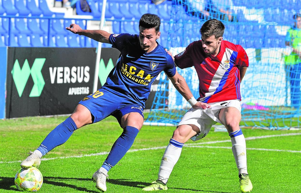 Mayoral defiende un balón ante la presencia de un jugador del Recreativo en febrero de 2020, cuando defendía la camiseta del UCAM. 