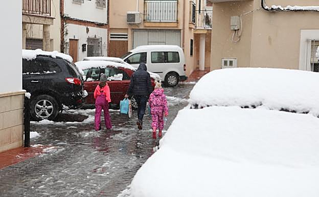 Una vecina de la pedanía lorquina de Coy pasea con sus dos hijas entre coches nevados.