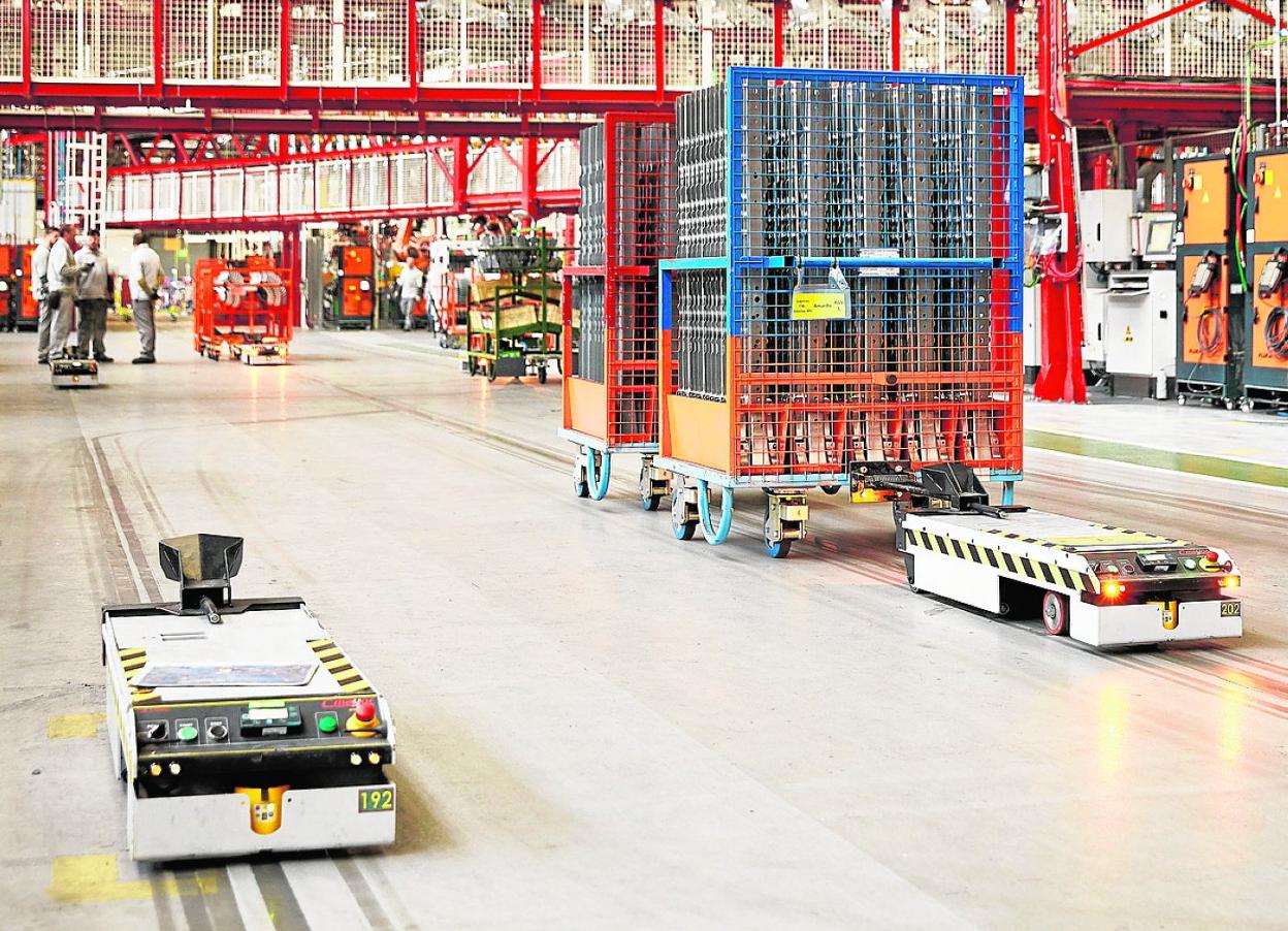 Pequeños 'cobots' desplazan componentes dentro de un almacén industrial. 
