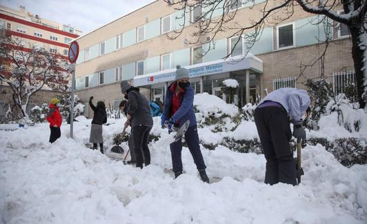 Varios vecinos ayudan a despejar los accesos a un hospital en Madrid.