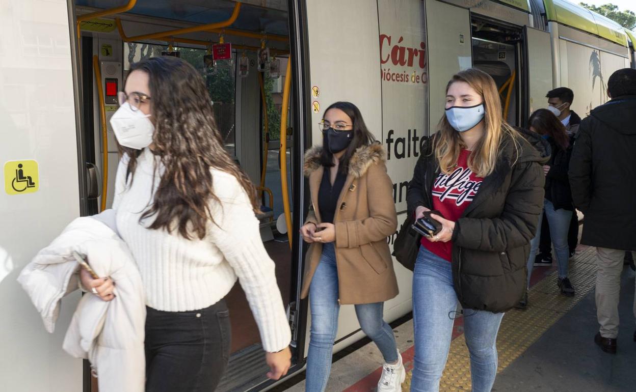 Tres jóvenes bajan del tranvía en plena hora punta de salida de las clases.