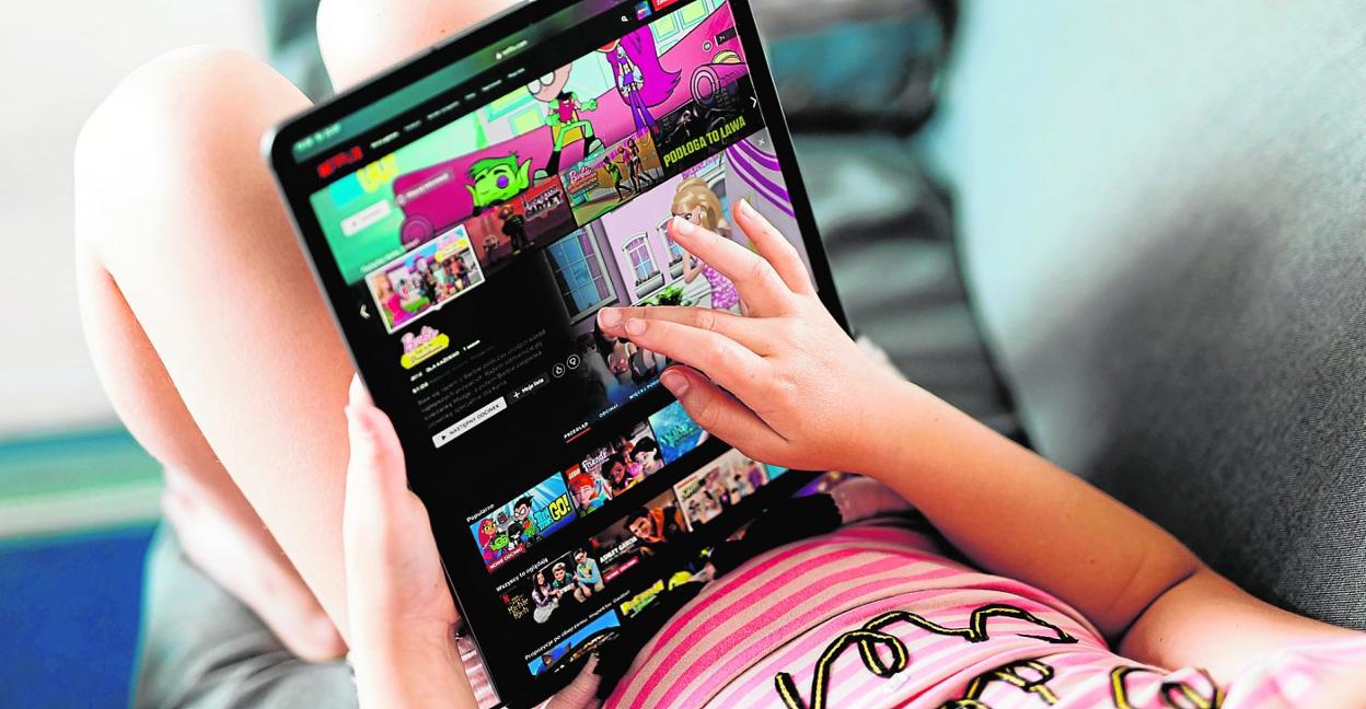 Una niña interactúa con su tableta para visualizar contenido multimedia. 