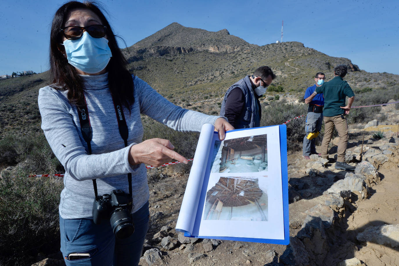La arqueóloga Consuelo Martínez muestra una imagen de cómo sería una de las casas de la aldea.