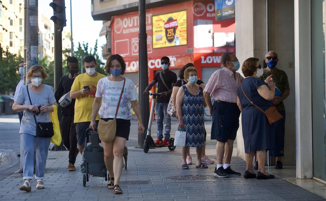 Un grupo de ciudadanos pasean con mascarillas por una calle dle barrio del Carmen, en Murcia.