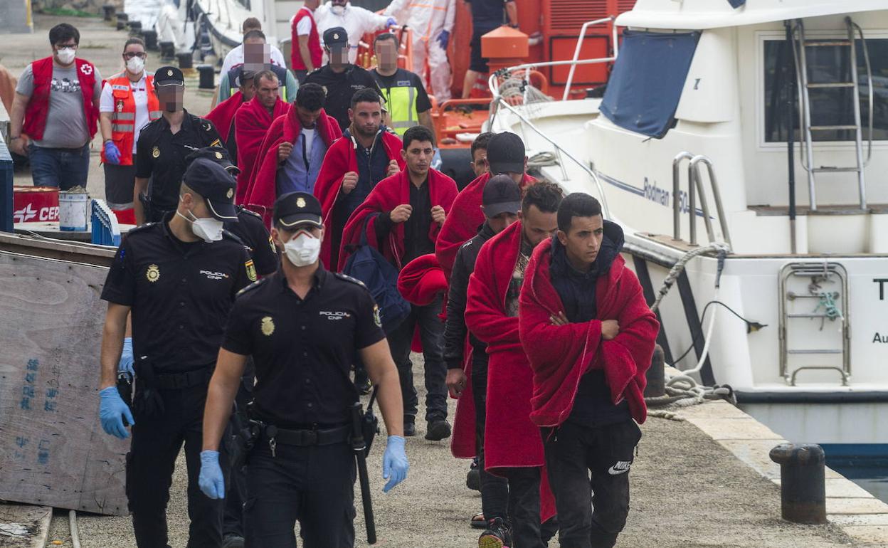 Agentes de la Policía Nacional custodian a un grupo de inmigrantes llegados en patera a Cartagena, en una foto de archivo.