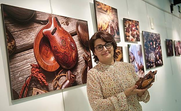  La historiadora Clara Alarcón posa con unas postizas antes de su conferencia, con imágenes de la exposición detrás. 