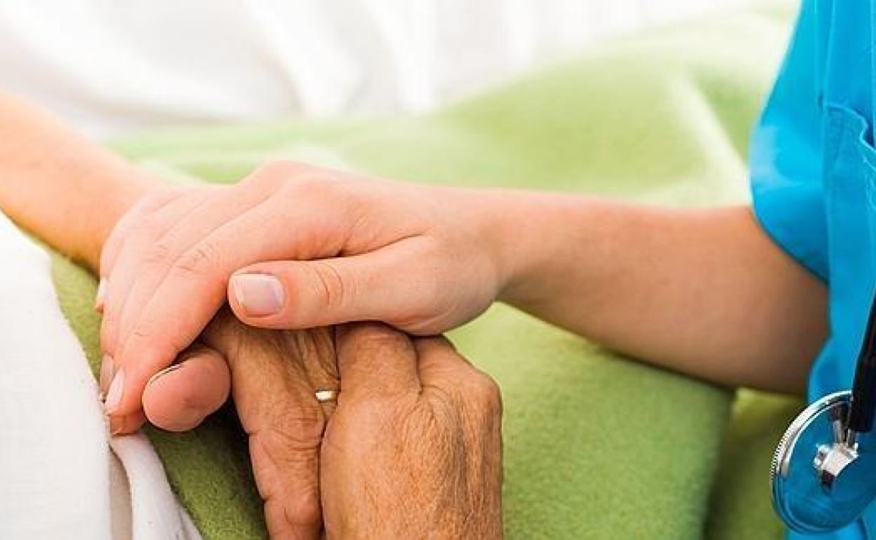 Una enfermera coge de la mano a un paciente en una foto de archivo.