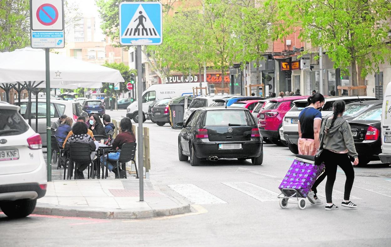 Dos mujeres pasan frente a la terraza de un bar en la calle Príncipe de Asturias, que soporta también un intenso tráfico. 