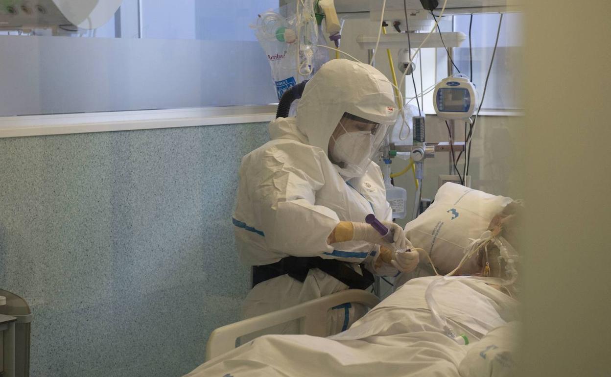 Una sanitaria atiende a un enfermo en la UCI del hospital Santa Lucía de Cartagena.