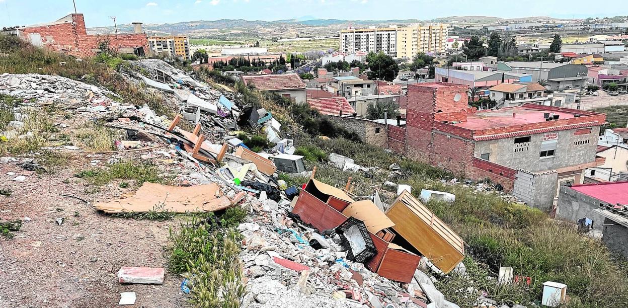 Imagen de la ladera este del Cabezo de la Cruz, con la Costera Norte al fondo, cubierta de escombros, enseres y demás basura. 