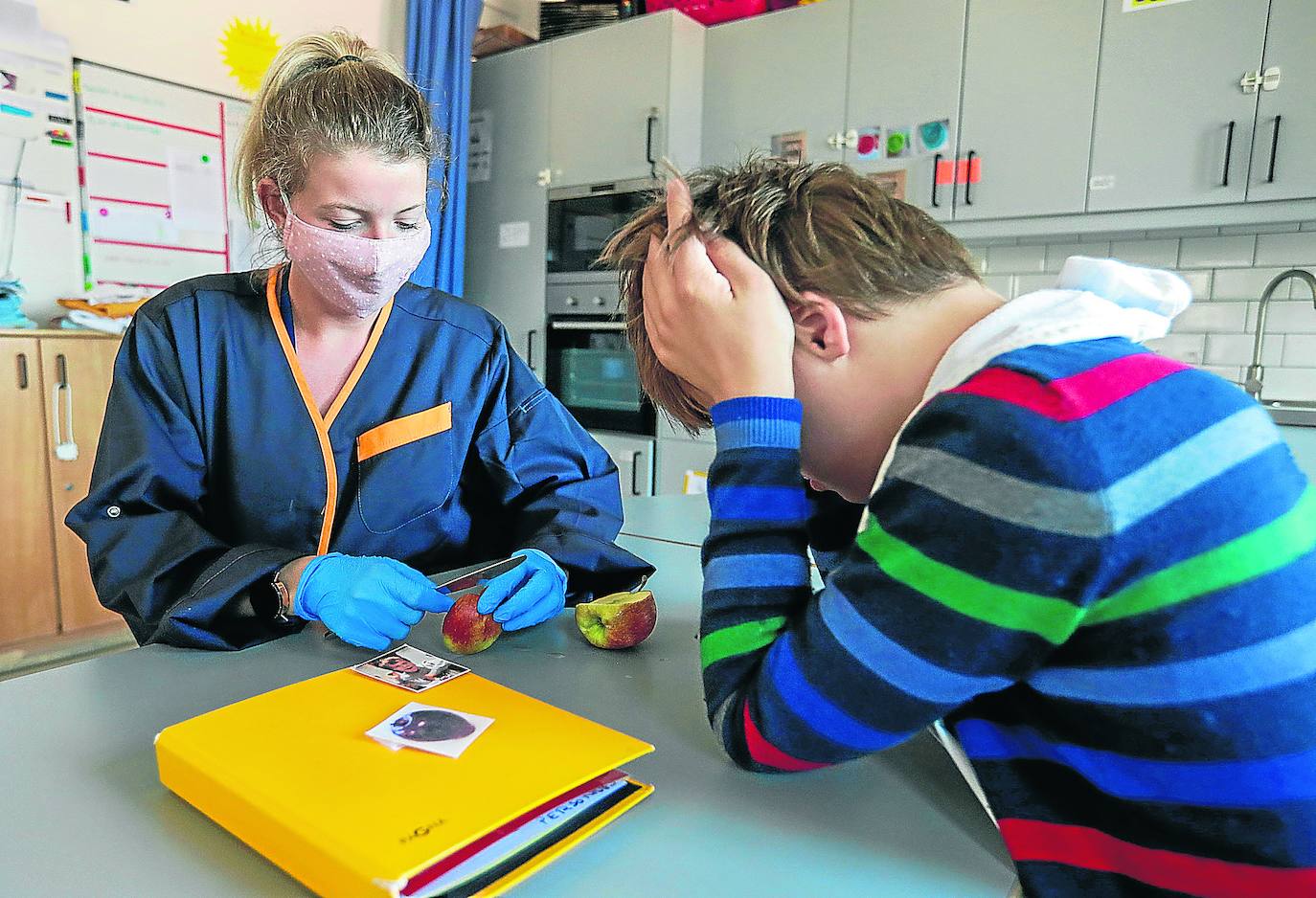 Apoyo profesional. Una monitora trabaja los protocolos de limpieza y alimentación con un adolescente que sufre síndrome de Down y autismo.