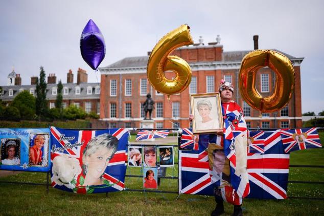 Un fan de Lady Di posa con una fotografía de ella frente al Palacio de Kensington, antes de la instalación de la estatua en su honor.