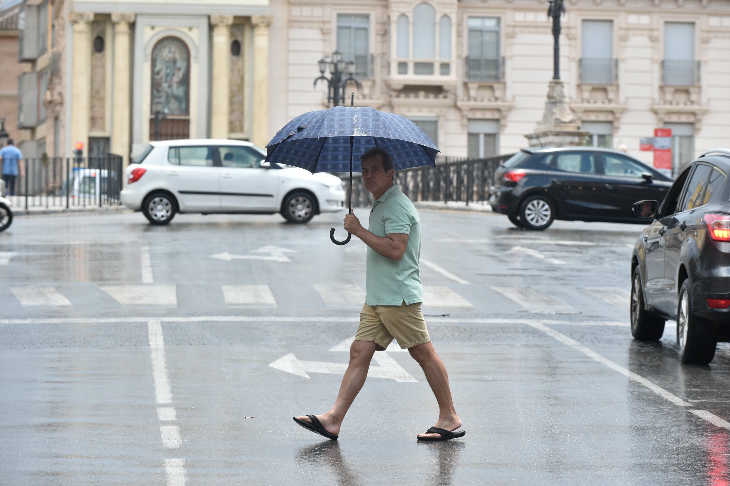 Un hombre se protege de la lluvia en Murcia.