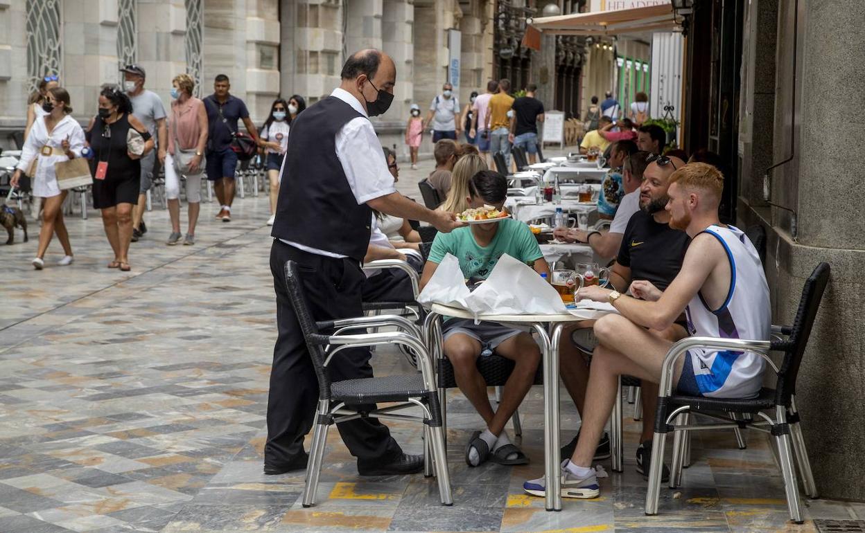 Un camarero atiende a unos clientes en una terraza en Cartagena, en agosto de este año.