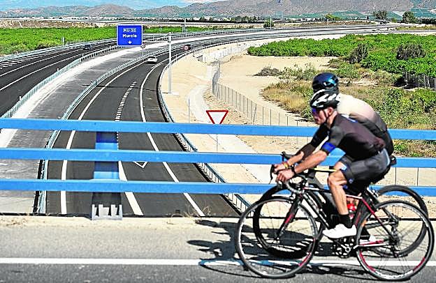 Dos ciclistas pasan por un viaducto sobre la autovía recién estrenada. 