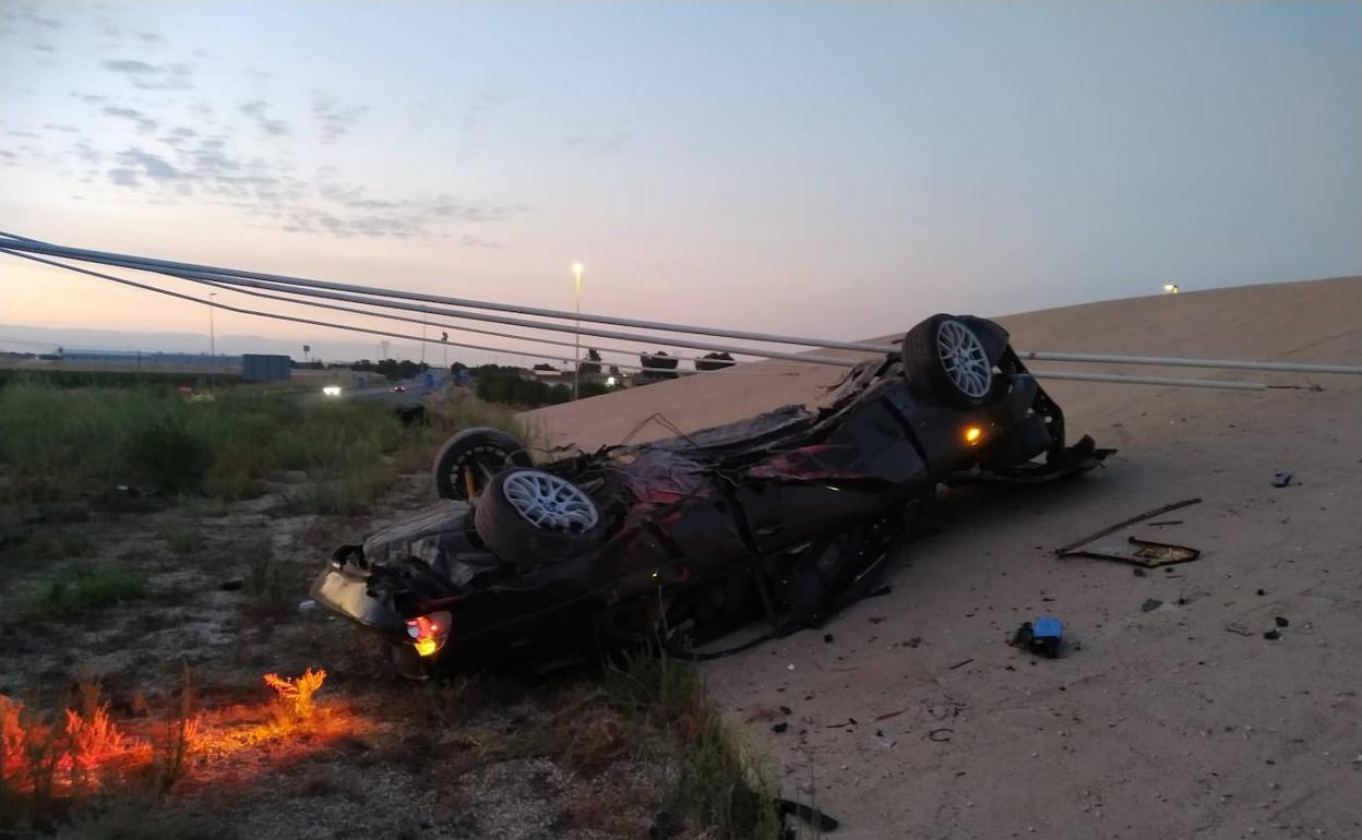 El coche quedó volcado dentro de la glorieta tras el impacto.