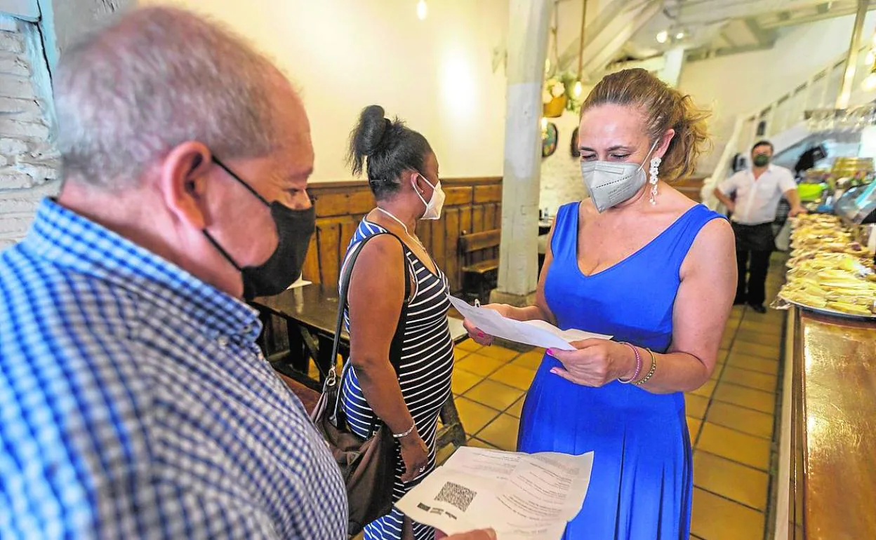La encargada de un restaurante santanderino examina los pasaportes Covid de sus clientes. 