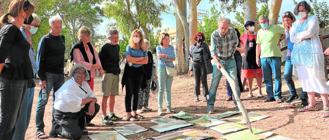 El pintor Pedro Cano, ayer, señala con una corteza de eucalipto las obras realizadas por sus alumnos en la primera jornada. 