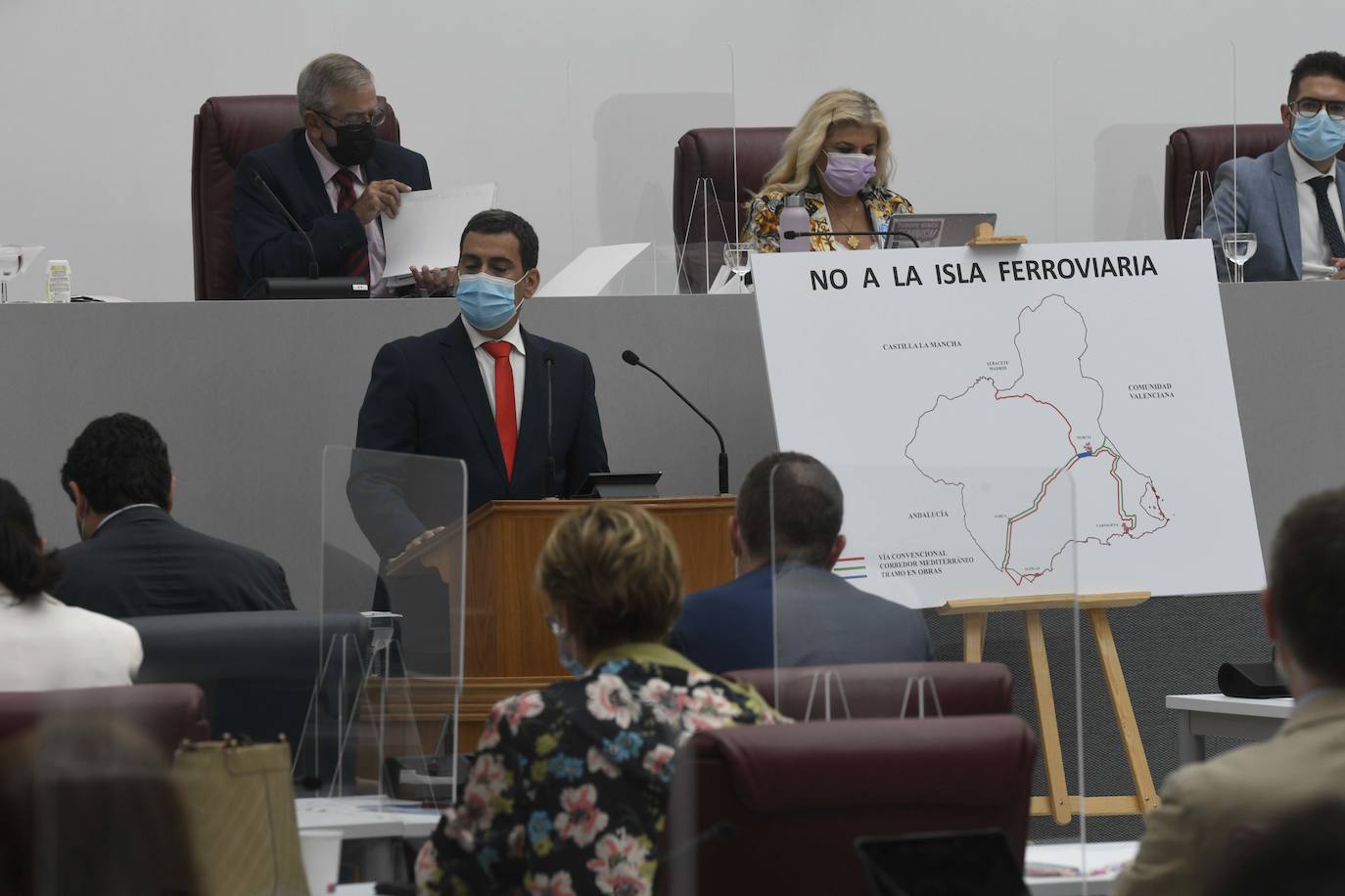 El consejero interviene en el Pleno con un cartel contra «la isla ferroviaria».