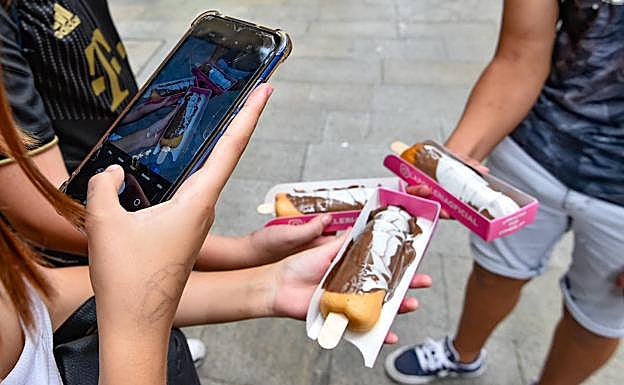 Varios clientes hacen fotos a sus 'pollofres', comprados en la inauguración de este viernes. 