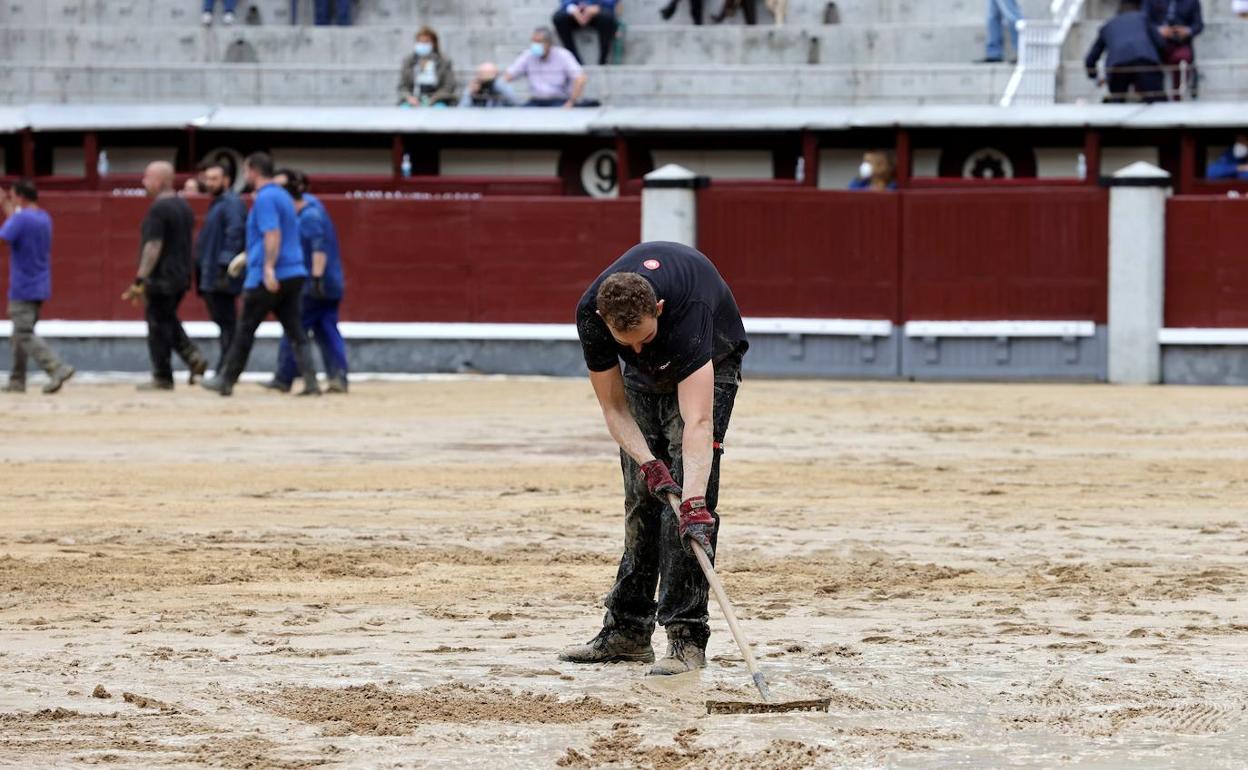 Operarios trabajan sobre el suelo de la plaza de toros de Las Ventas tras las lluvias de este viernes en Madrid.