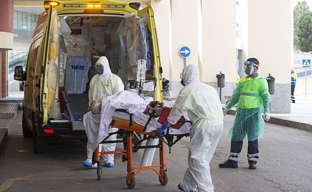 Profesionales del 061 trasladan a un paciente, en el acceso al servicio de Urgencias de La Arrixaca.