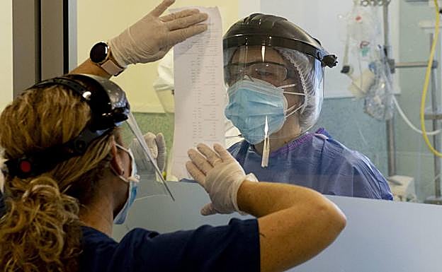 Dos sanitarios se comunican a través de un cristal en la UCI del Santa Lucía.