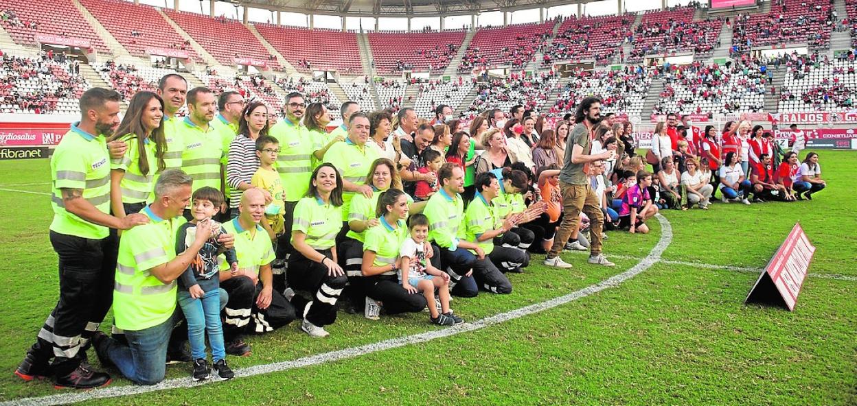 Los homenajeados y algunos de sus familiares, sobre el césped del Enrique Roca. 