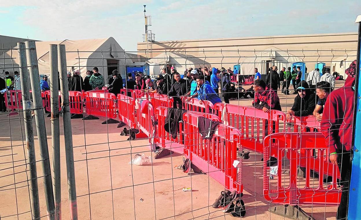 Grupos de inmigrantes argelinos llegados en pateras, ayer ante las carpas habilitadas en el muelle de Escombreras. Pasan en este campamento un máximo de 72 horas. 