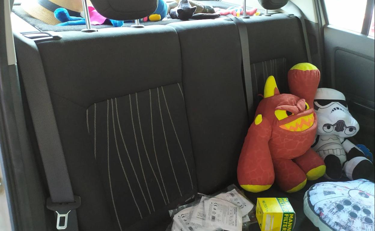 El asiento trasero de un coche con varios objetos encima.