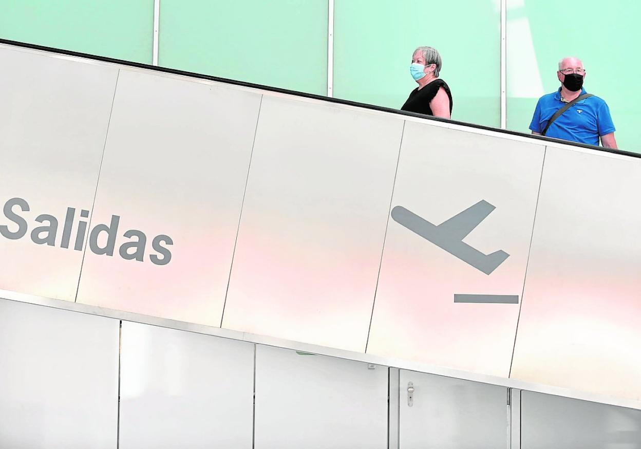Una pareja sube por una escalera de la terminal de pasajeros del aeropuerto de Murcia. 