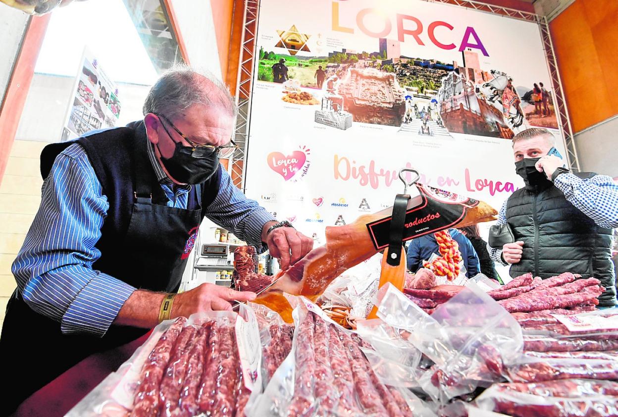 Un visitante espera a recibir un plato de embutidos en el expositor de Lorca, ayer a mediodía. 