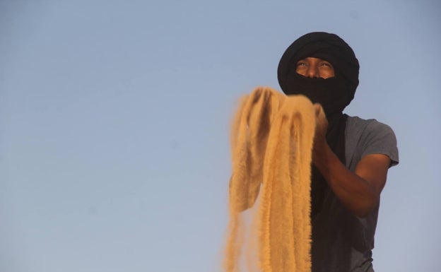 Tateh con turbante y arena del desierto del Sáhara entre las manos.