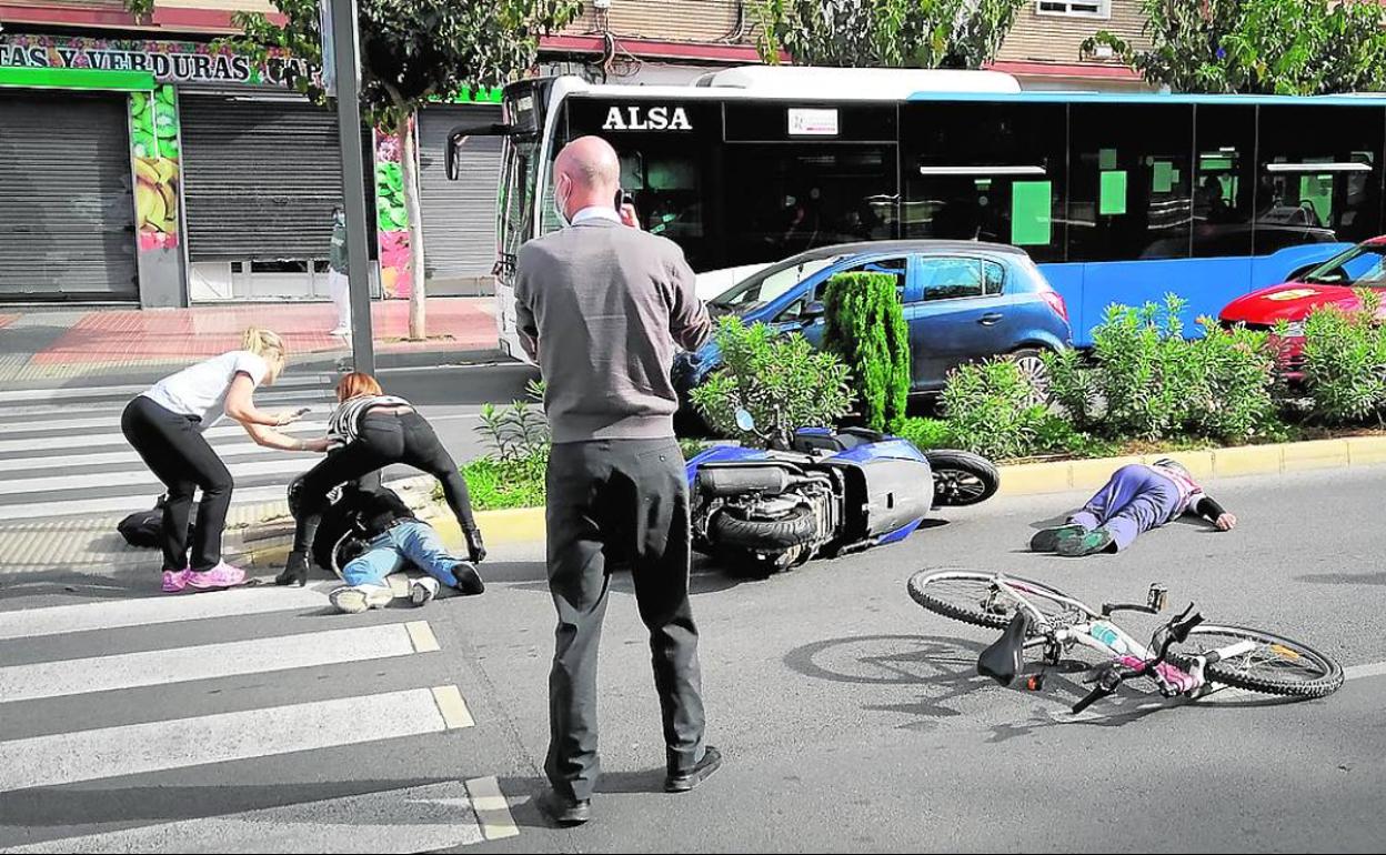 Un herido es atendido por dos viandantes, mientras otro está tendido en el suelo, en Capitanes Ripoll. 