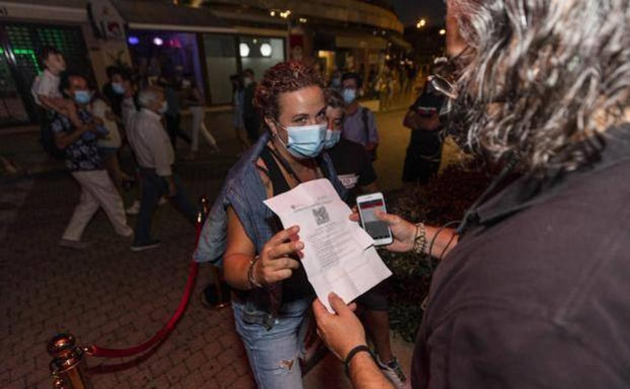 Un trabajador pide el certificado Covid a una clienta en la puerta de un local.